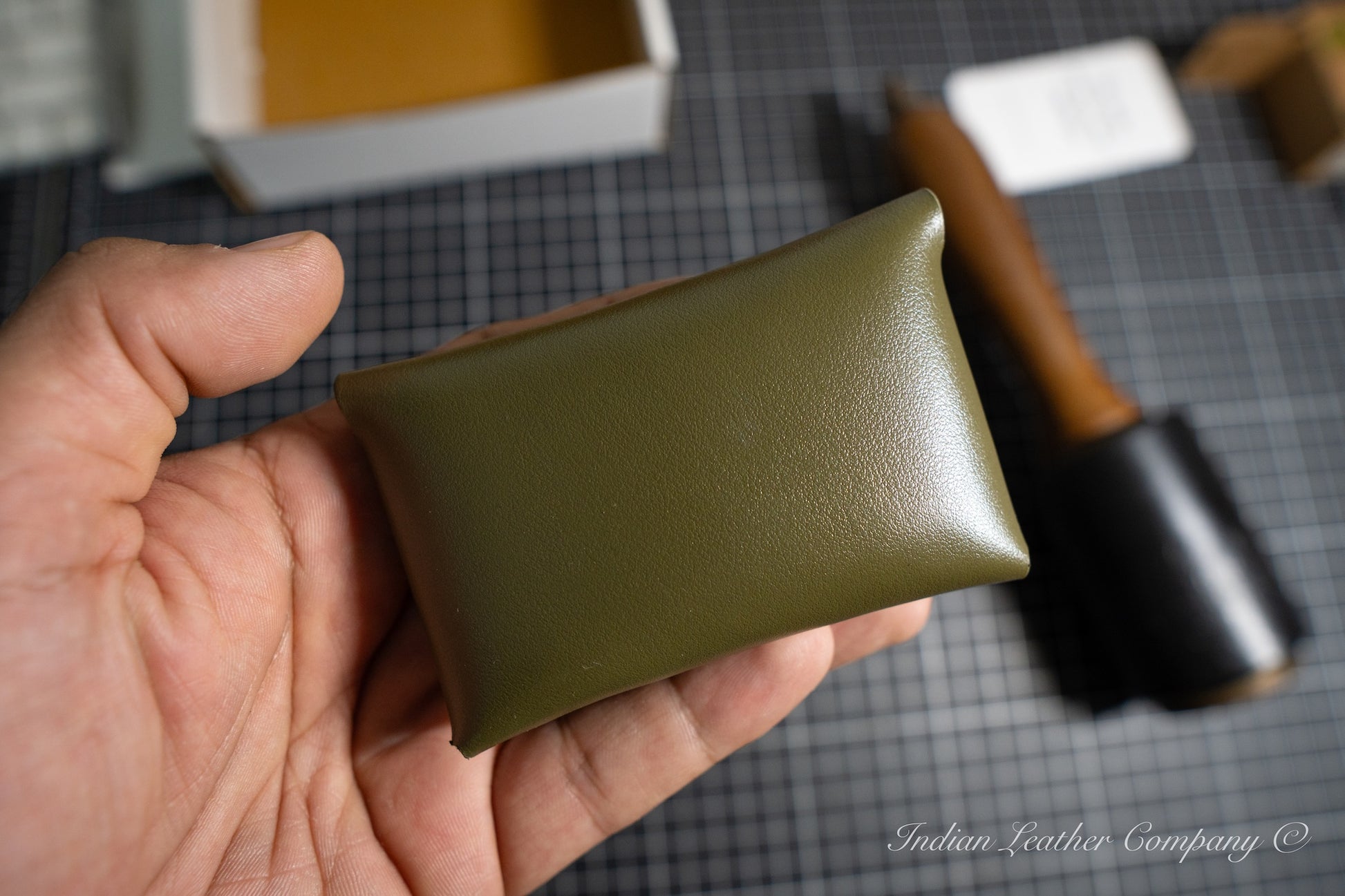 Hand holding a full grain green leather wallet from Indian Leather Company