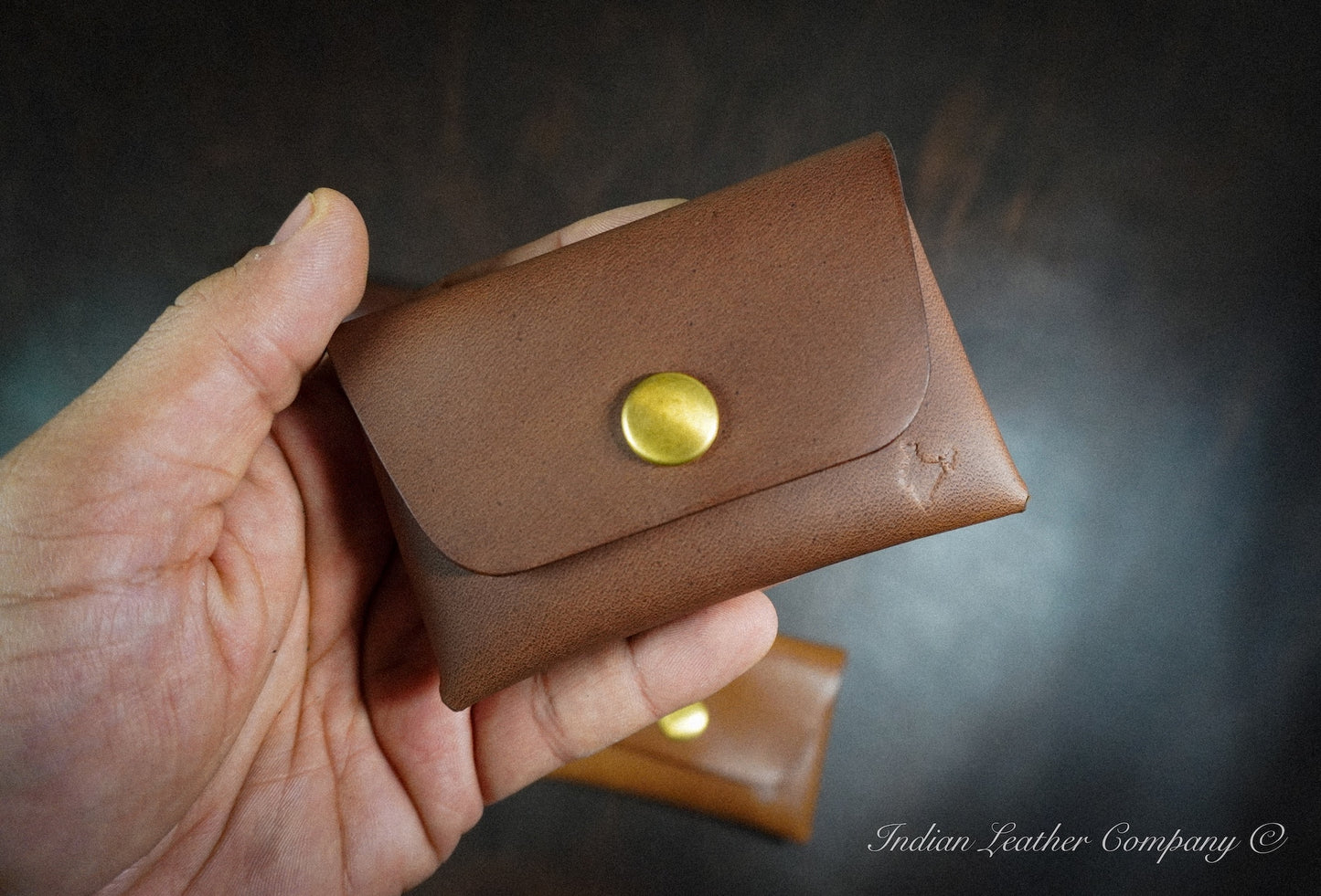 Handmade minimalist leather snap wallet designed for everyday carry, shown held in hand
