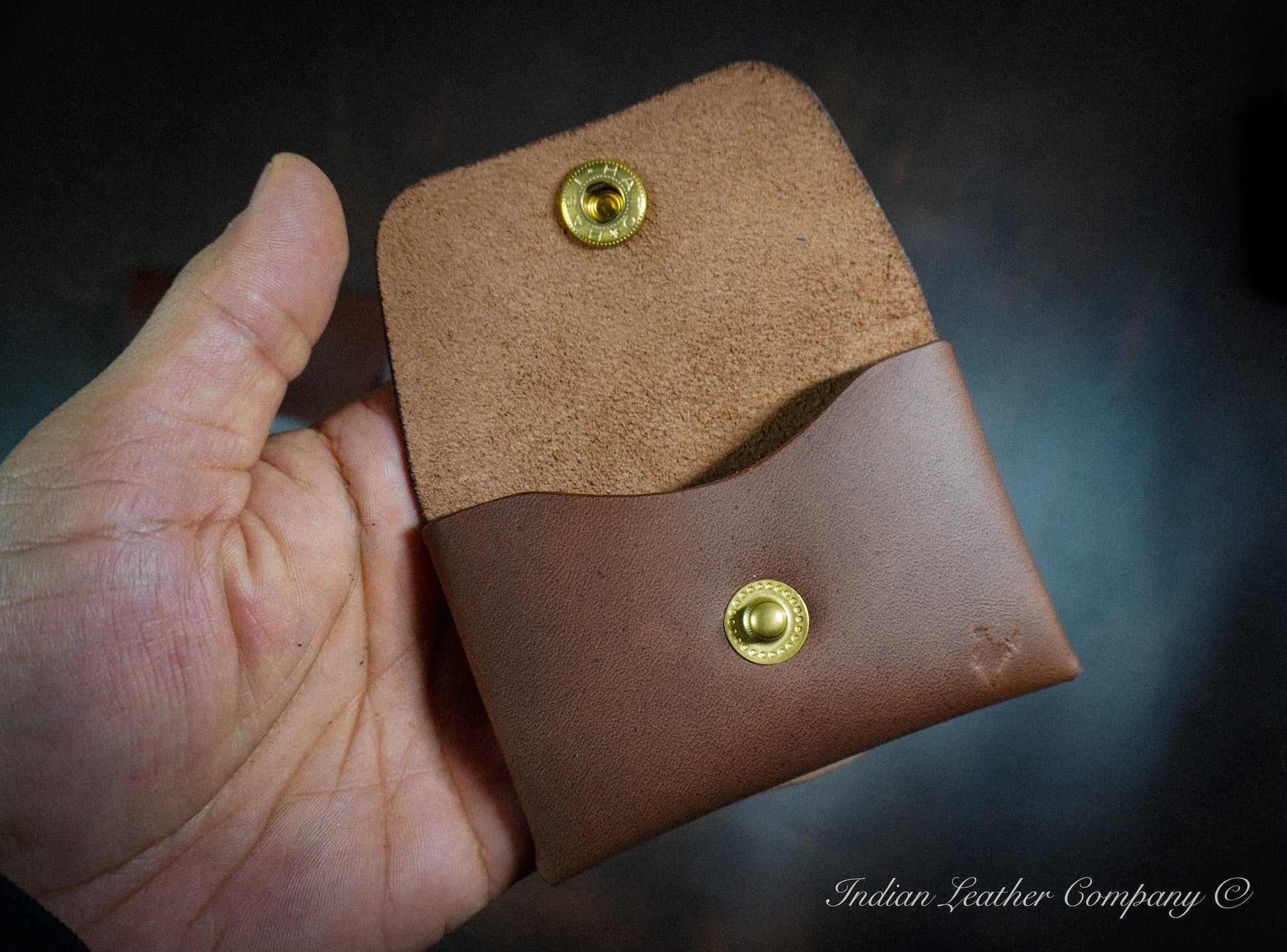 Waxy pull-up leather stitchless wallet showing natural color variation and folded snap closure design