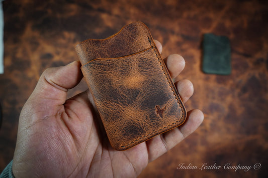 Handcrafted Outrider EDC wallet made from hand-waxed Latigo leather, shown in hand with rugged patina and wrap-around minimalist design.