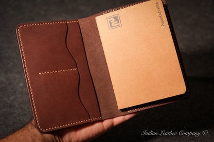 An open brown leather Journal cover held in a hand, showing an A6 size notebook insert 