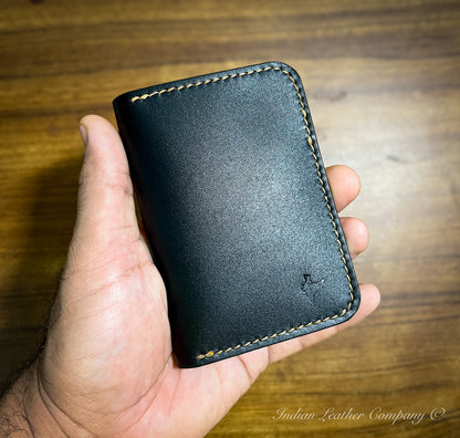 A close-up image of the Himalayan card wallet, showcasing its sleek, minimalist design made from full grain vegetable-tanned leather. The wallet is neatly folded, revealing its smooth texture and rich color.