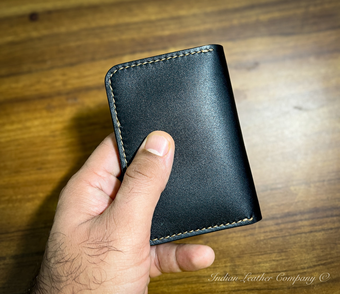 A close-up shot focusing on the smooth, rich texture of the full grain vegetable-tanned leather, showcasing its natural color and grain pattern. The image highlights the wallet's high-quality material and craftsmanship.